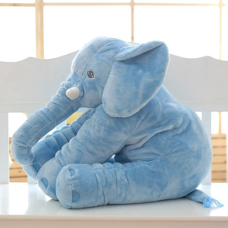 Blue elephant plush toy on a white surface with a light wooden background