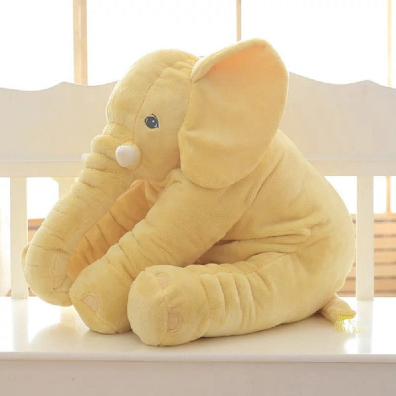 Yellow elephant plush toy on a white surface with a light background