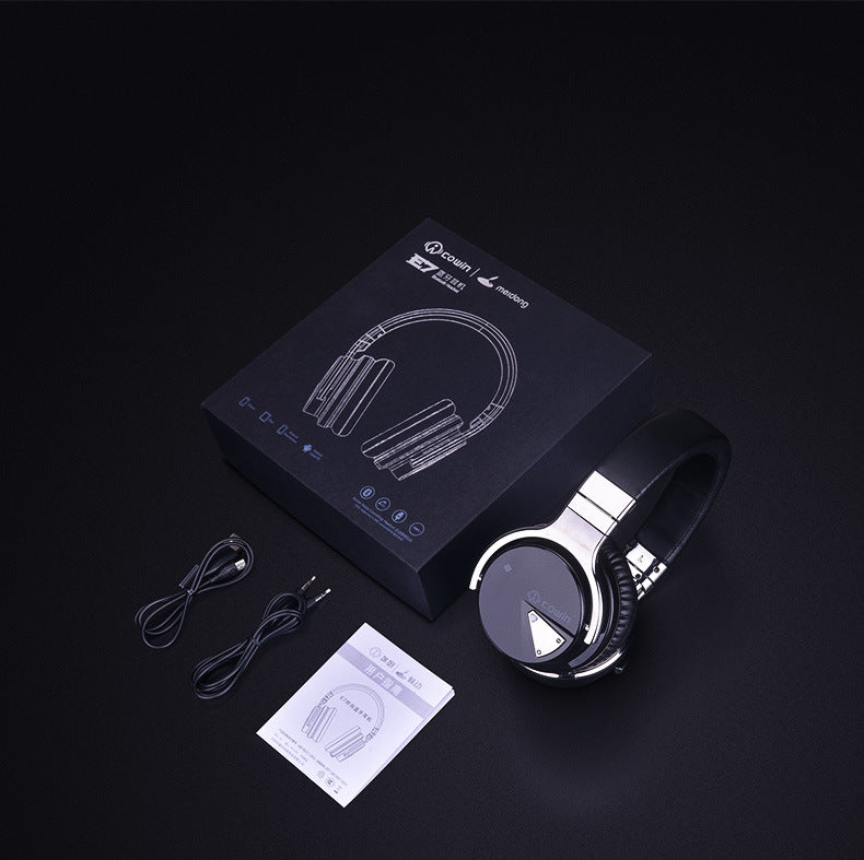 Headphones with packaging, cable, and manual on a dark background