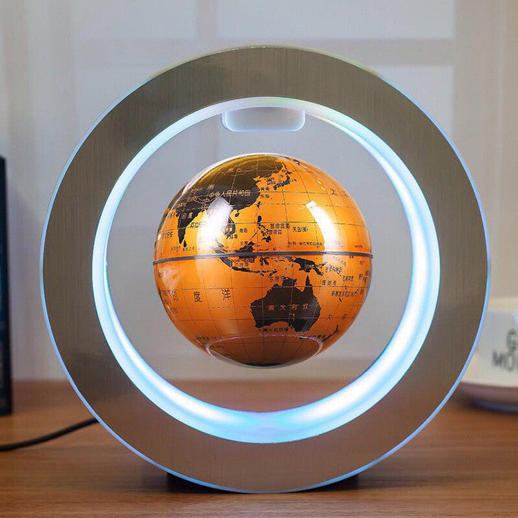 Levitating orange globe with a silver circular base on a wooden surface.