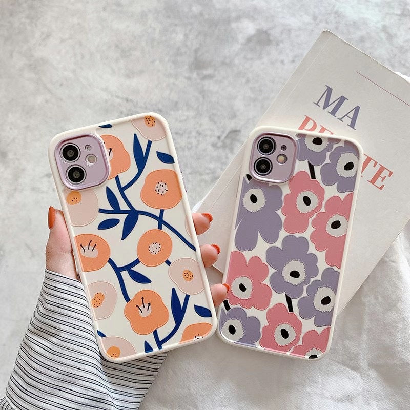 Two floral phone cases held by a person against a light background