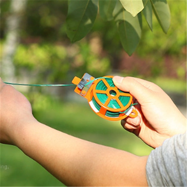 Hand holding a green and orange spool with a blurred green outdoor background