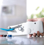 Hand holding a white sewing machine with blue accents on a reflective surface.