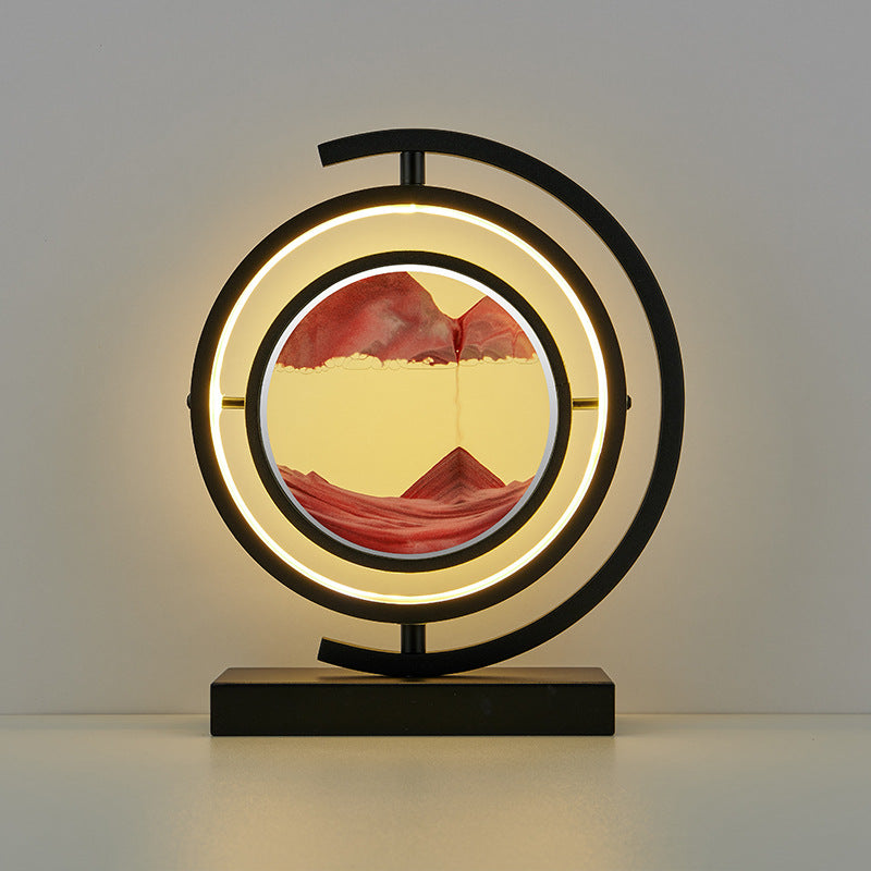 Decorative table lamp with circular design and mountain landscape inside, on a plain background.