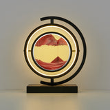 Decorative table lamp with circular design and mountain landscape inside, on a plain background.