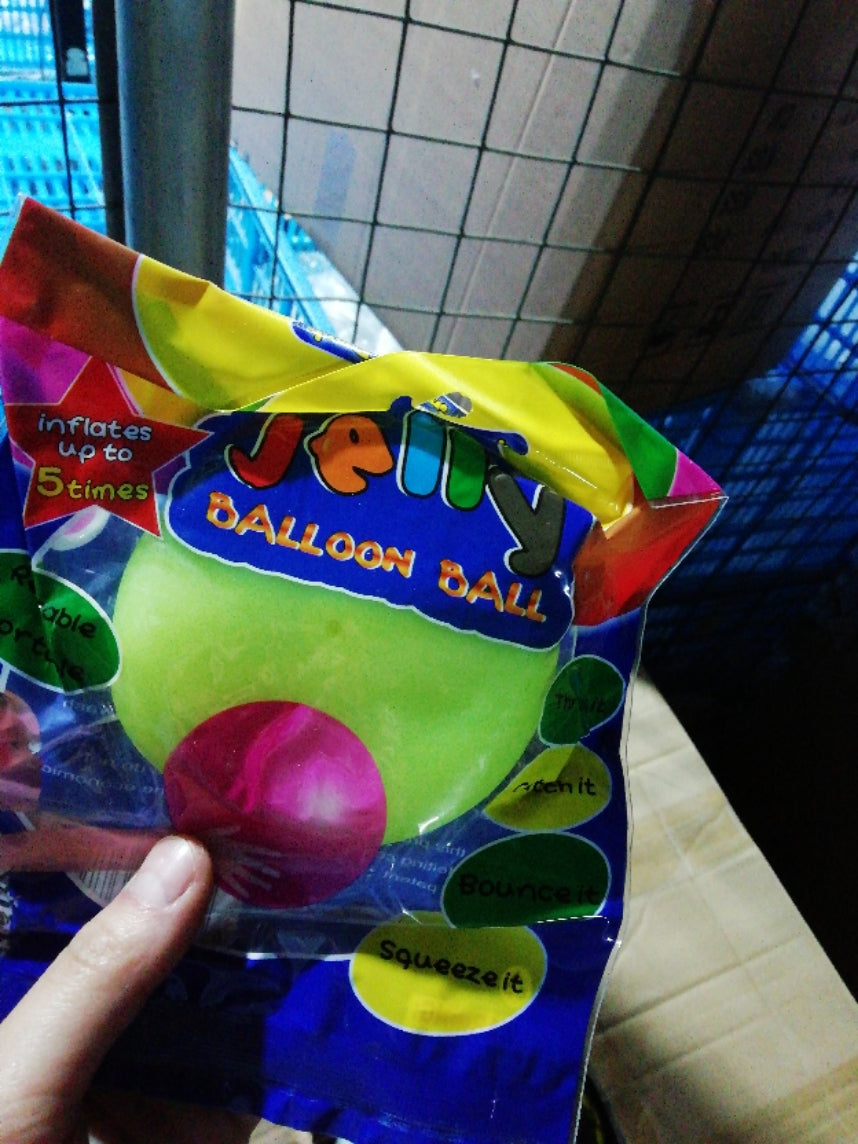 Packaged balloon ball with colorful packaging held by a hand against a tiled wall background.