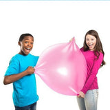 Two people holding a large pink bubble gum ball against a white background