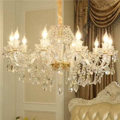 Crystal chandelier hanging in a room with a sofa and decorative curtains.