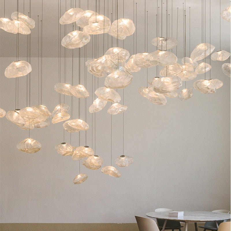 Modern chandelier with glass shades hanging in a room with a dining table.