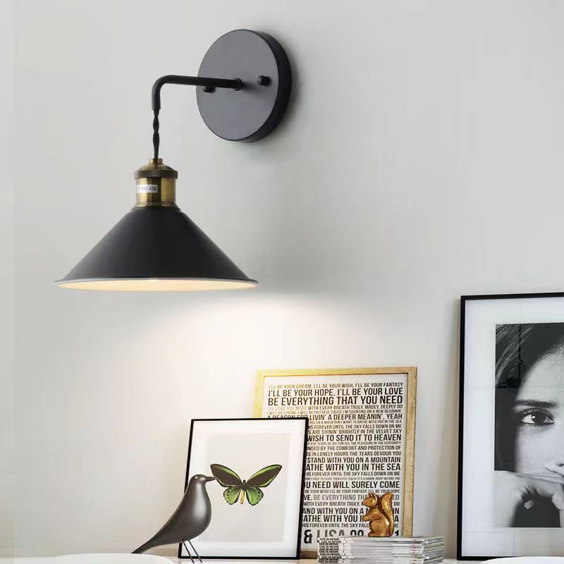 Black wall lamp fixture on a white wall with decorative items below.