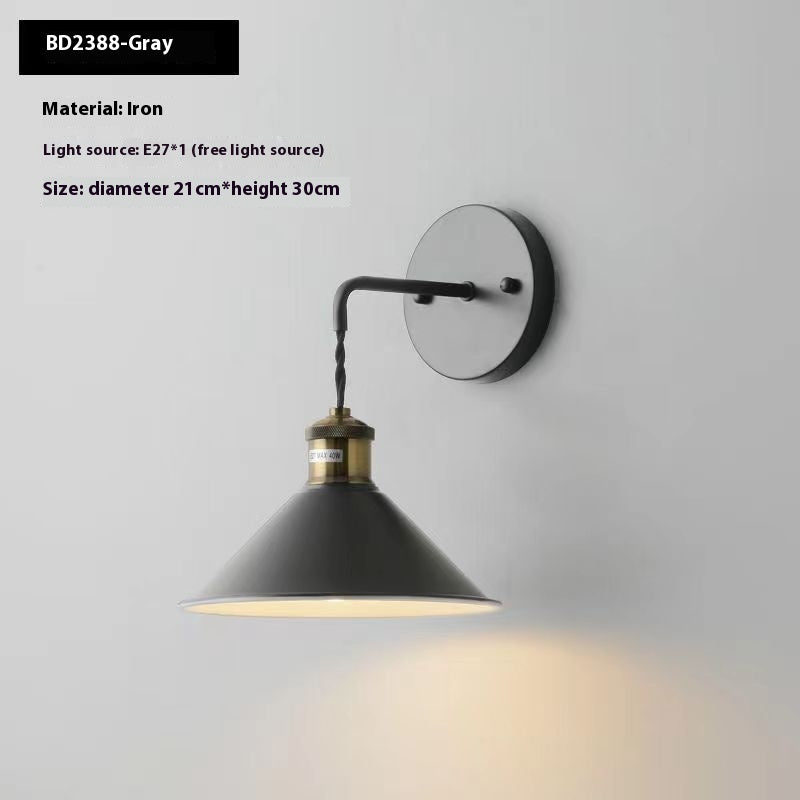 Wall-mounted lamp with black shade and brass accents on a gray background