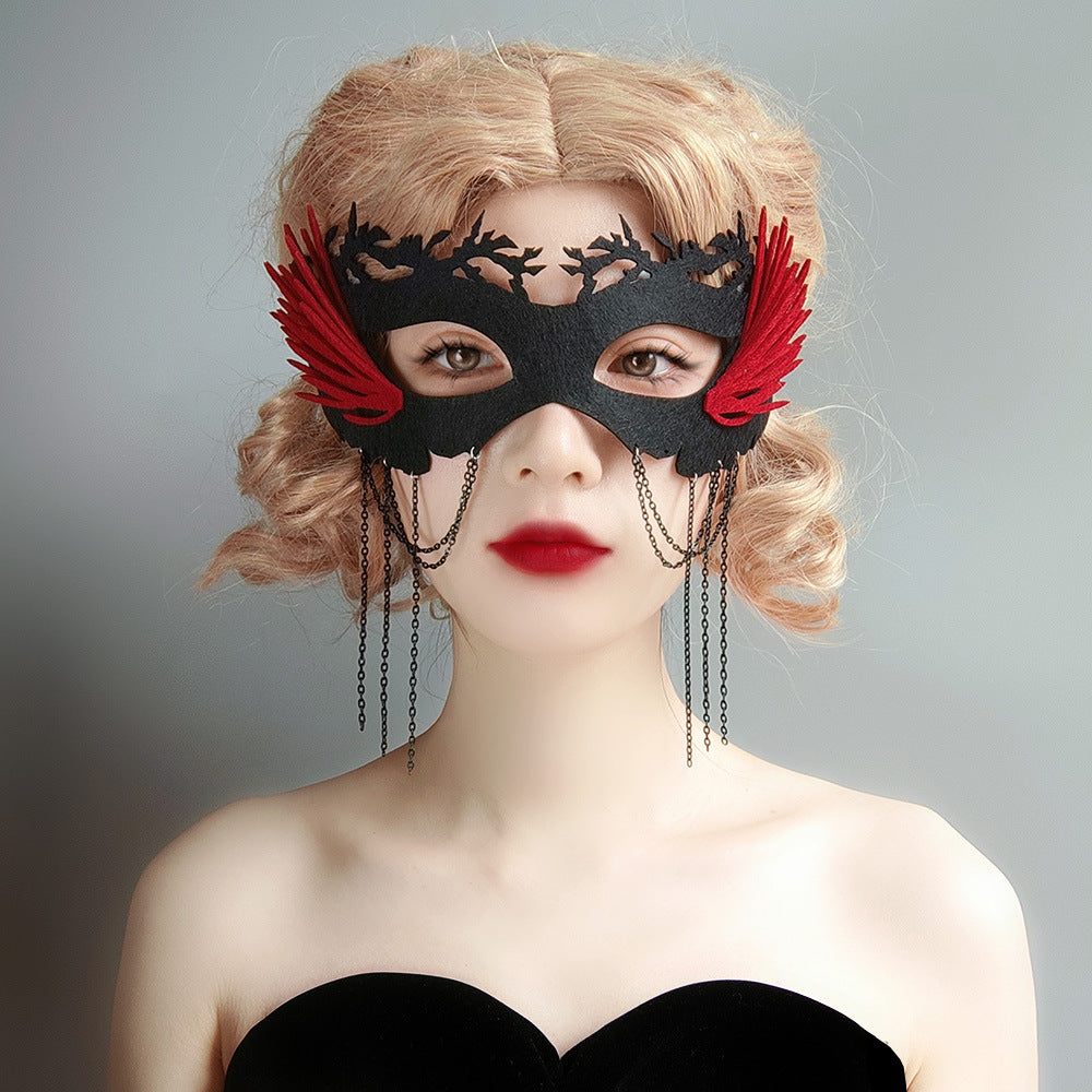 Woman wearing a black lace mask with red feathers and chains on a gray background