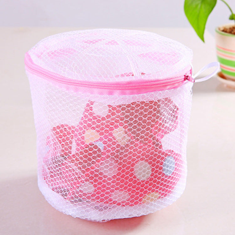 Pink mesh laundry bag with a zipper on a light surface.