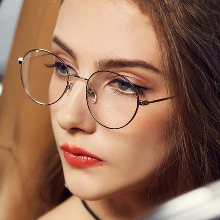 Close-up of a person wearing round glasses with a blurred background