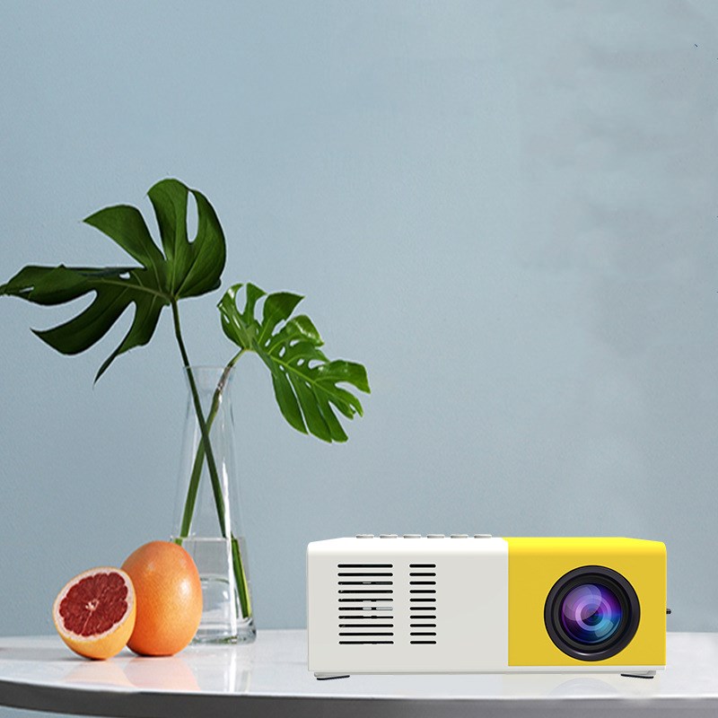 Yellow and white projector on a table with a plant and fruit in the background
