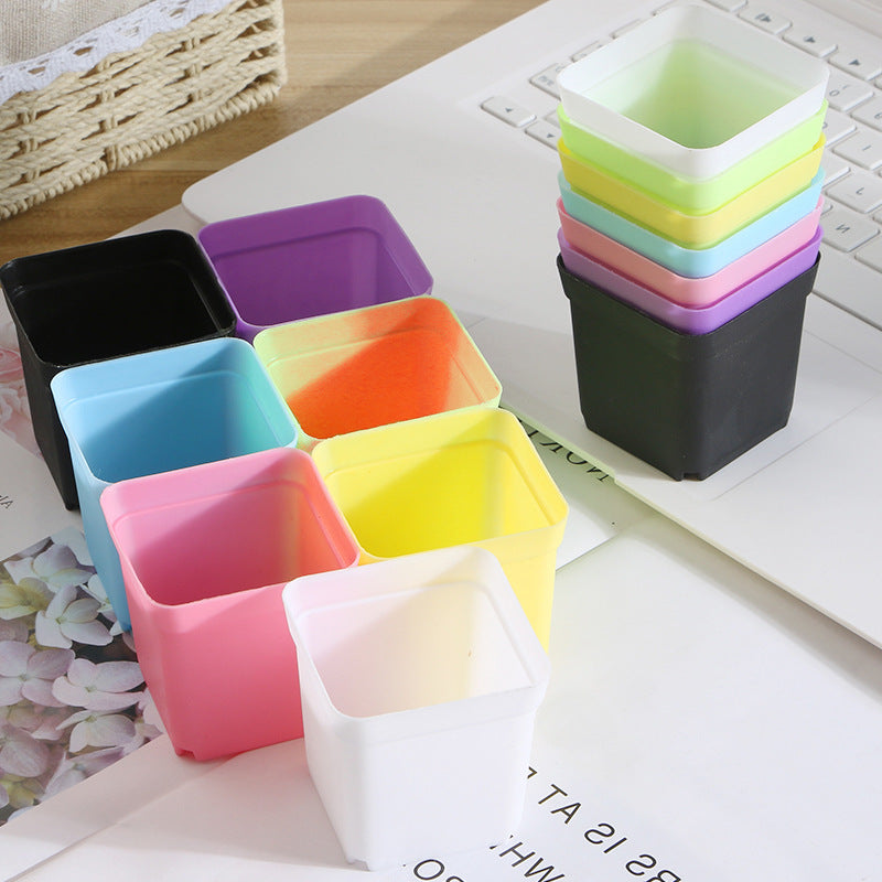 Colorful square plastic pots on a desk with a laptop
