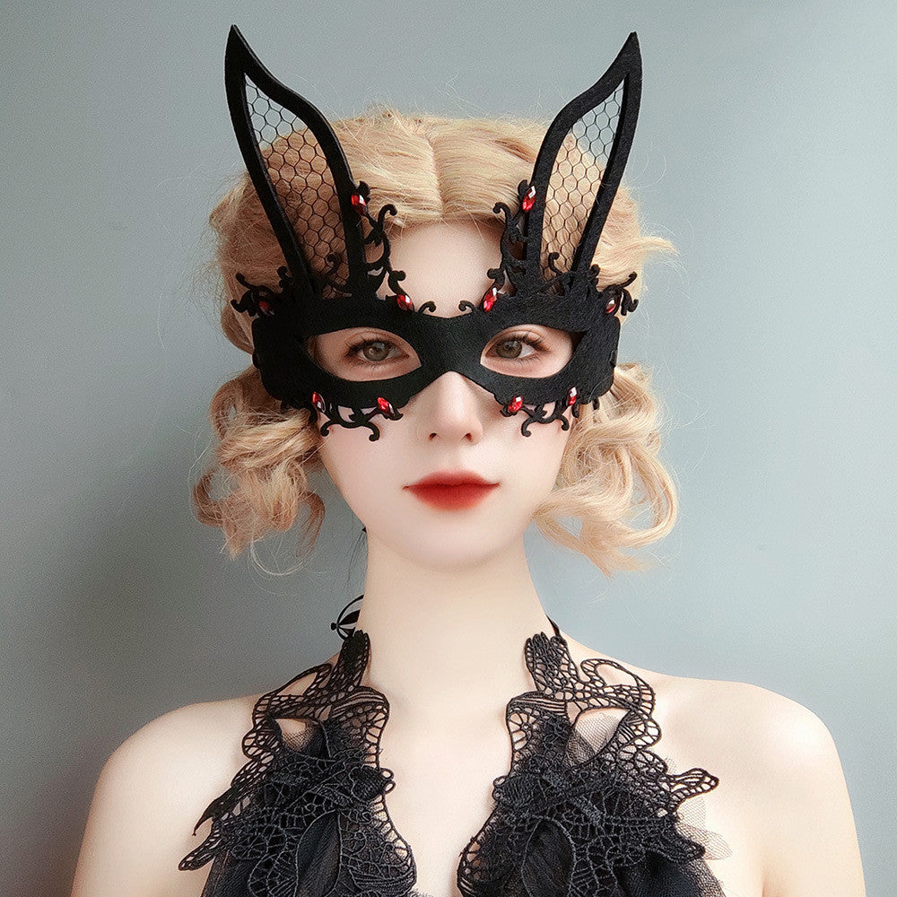 Person wearing a black lace bunny mask and costume against a gray background