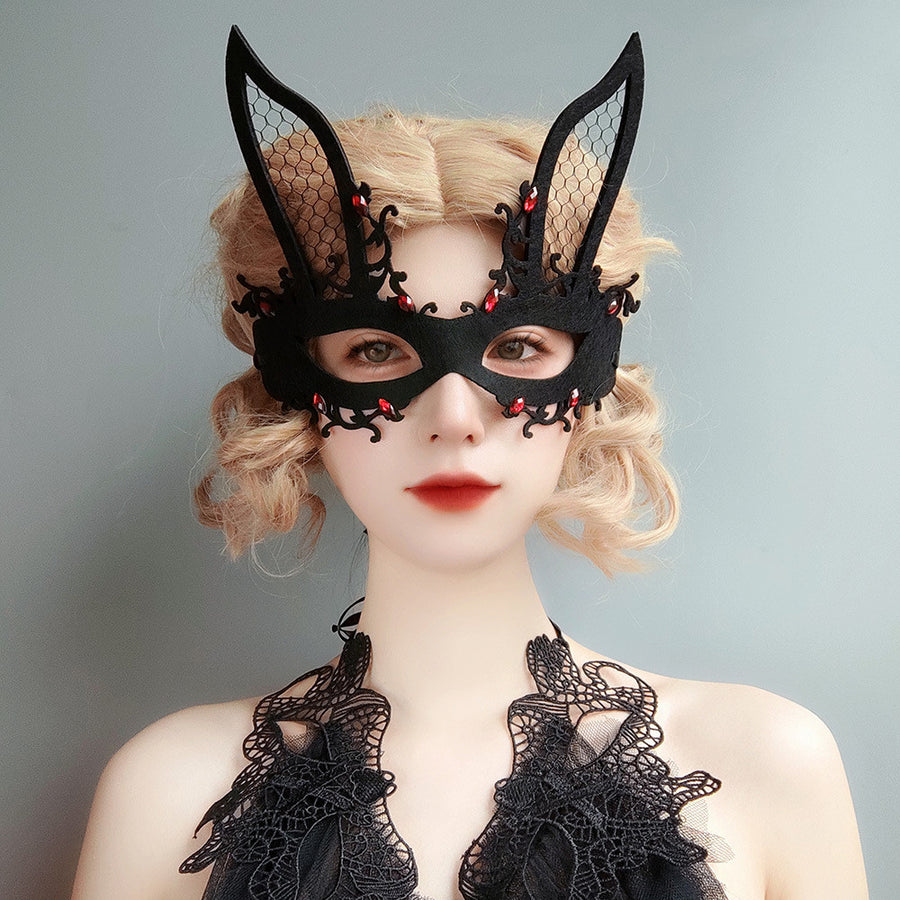 Person wearing a black lace bunny mask and costume against a gray background