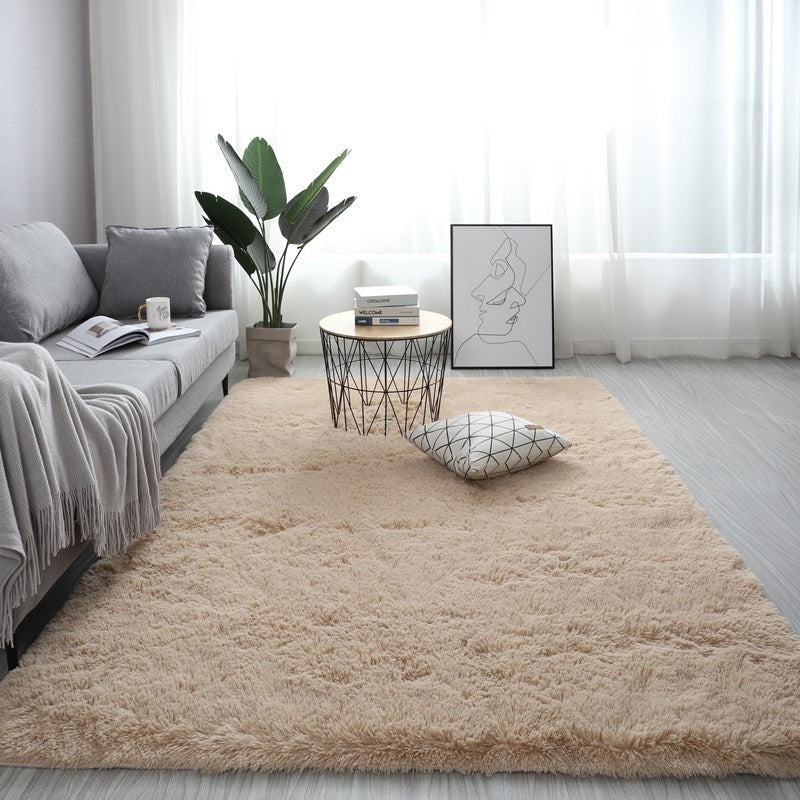 Beige rug in a living room with a sofa, coffee table, and decorative items.