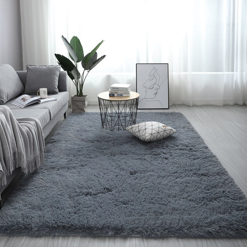 Living room with a gray rug, sofa, coffee table, and decorative items.