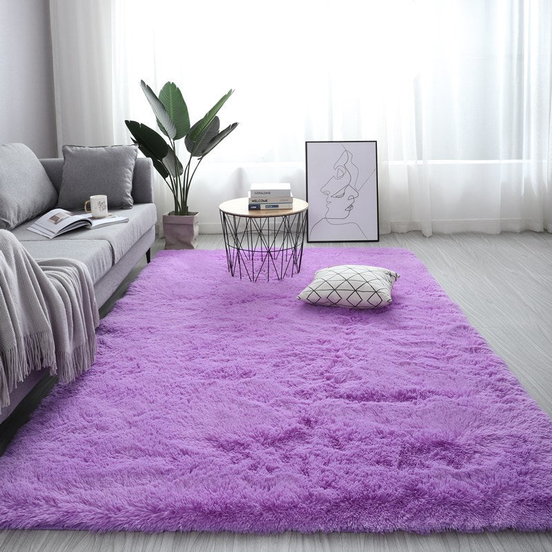 Living room with a purple rug, gray sofa, and decorative elements.