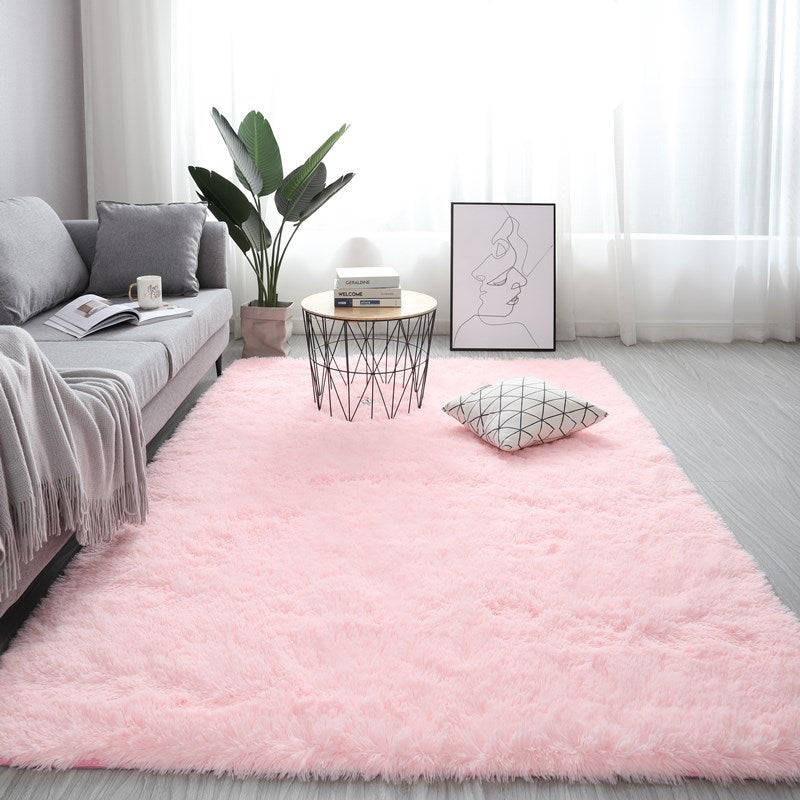 Living room with a pink rug, gray sofa, and decorative elements.