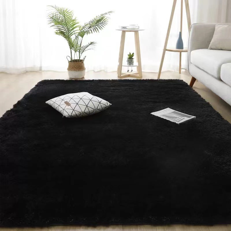 Black rug in a living room with a white sofa, plant, and small table.