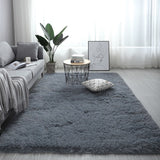 Living room with a gray rug, sofa, coffee table, and decorative items.
