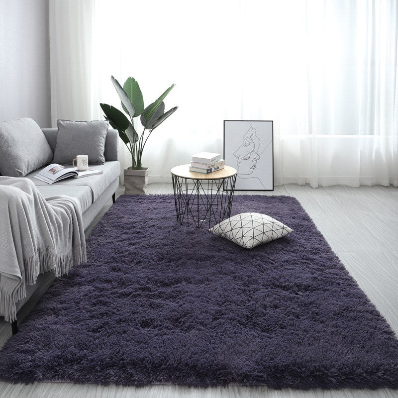 Living room with a purple rug, gray sofa, and decorative items.