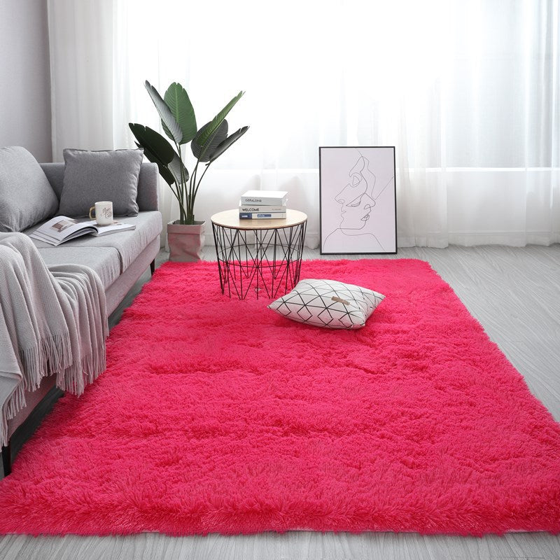 Living room with a pink rug, gray sofa, and decorative items.