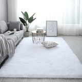 Modern living room with a white rug, gray sofa, and decorative items.