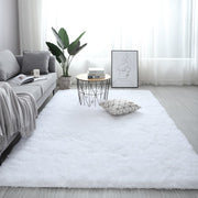 Modern living room with a white rug, gray sofa, and decorative items.