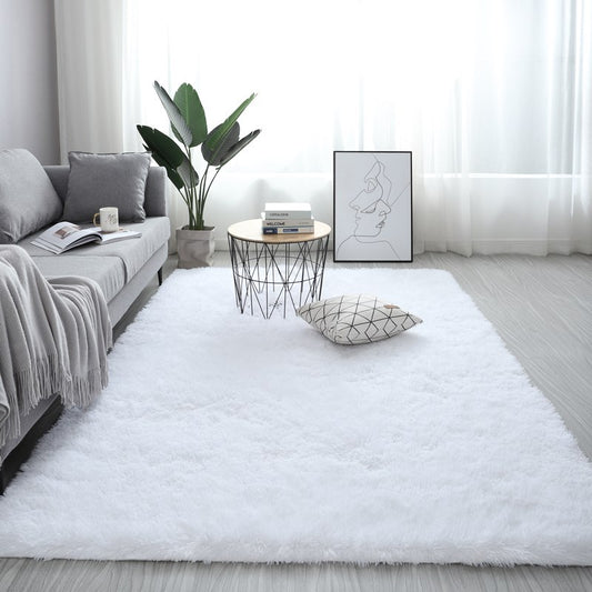 Modern living room with a white rug, gray sofa, and decorative items.