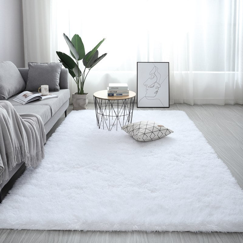 Modern living room with a white rug, gray sofa, and decorative items.