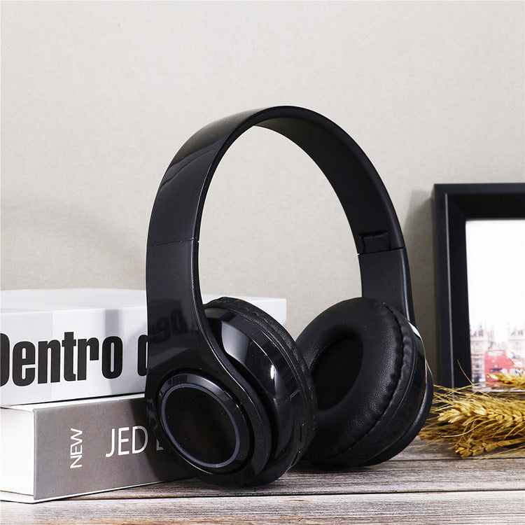 Black headphones on a surface with books and a framed picture in the background