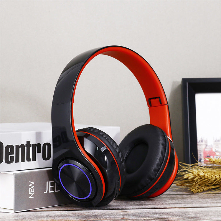 Black and red headphones on a surface with books and a picture frame in the background