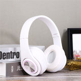 White headphones on a wooden surface with books and a picture frame in the background