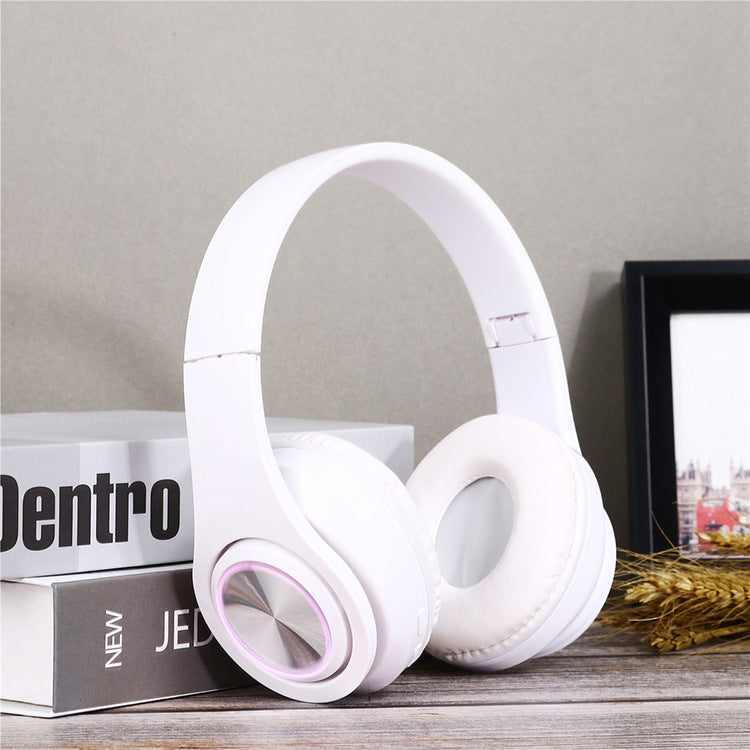 White headphones on a wooden surface with books and a picture frame in the background
