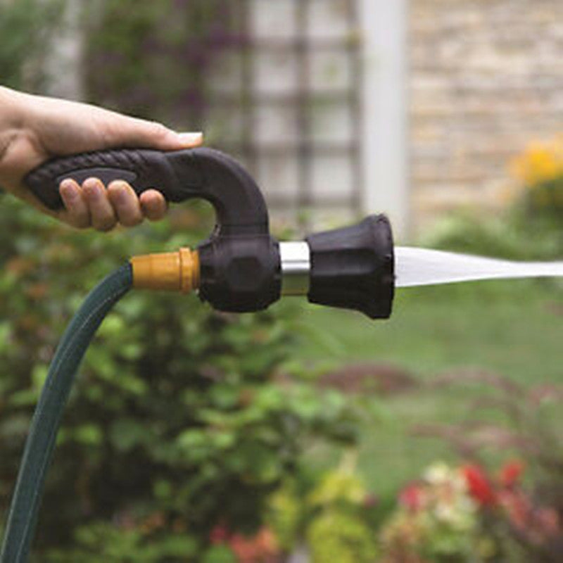 Hand holding a garden hose with a nozzle in a garden setting