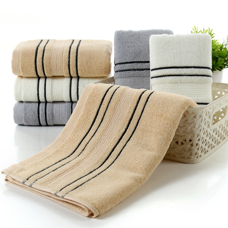 Set of folded towels in beige, gray, and white with black stripes on a white background.