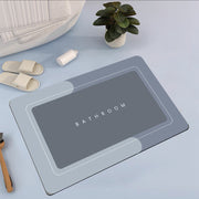 Gray bath mat with 'Bathroom' text on a light blue surface, surrounded by bathroom items.