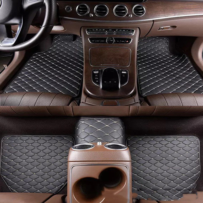 Car interior with quilted black floor mats and brown dashboard.