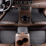 Car interior with quilted black floor mats and brown dashboard.