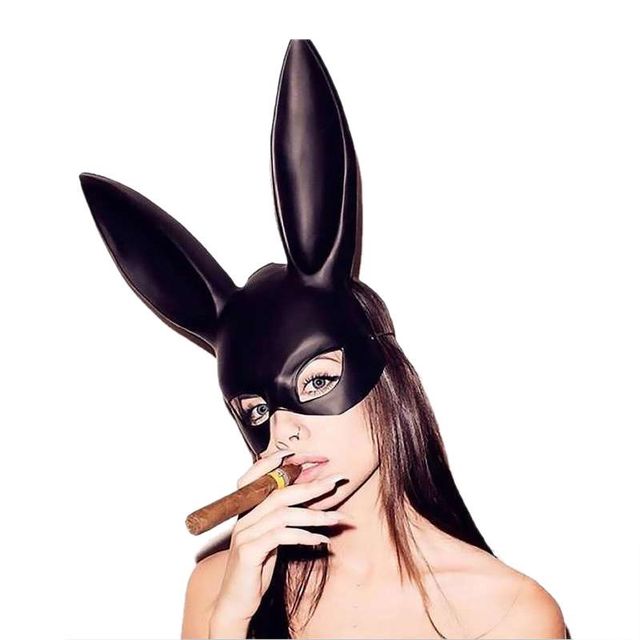 Person wearing a black bunny mask holding a cigar on a white background