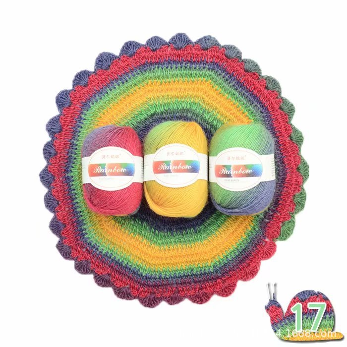 Three balls of yarn in red, yellow, and green on a colorful crocheted rainbow-patterned surface.