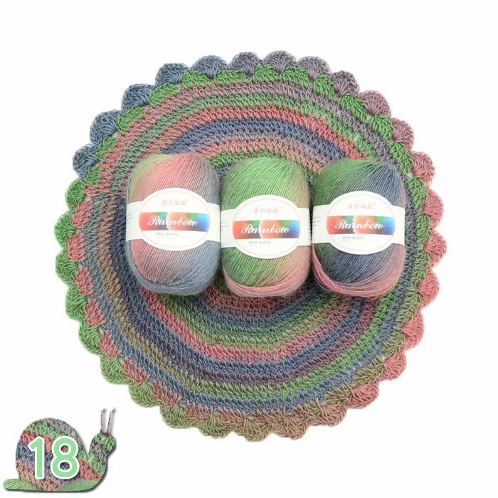 Three balls of yarn with labels inside a crocheted rainbow-patterned basket on a white background.