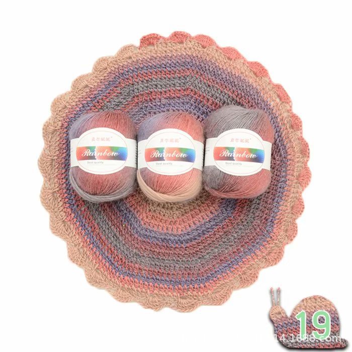 Three balls of yarn with labels on a crocheted yarn bowl against a white background.