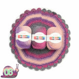 Three balls of yarn with labels on a crocheted circular mat.