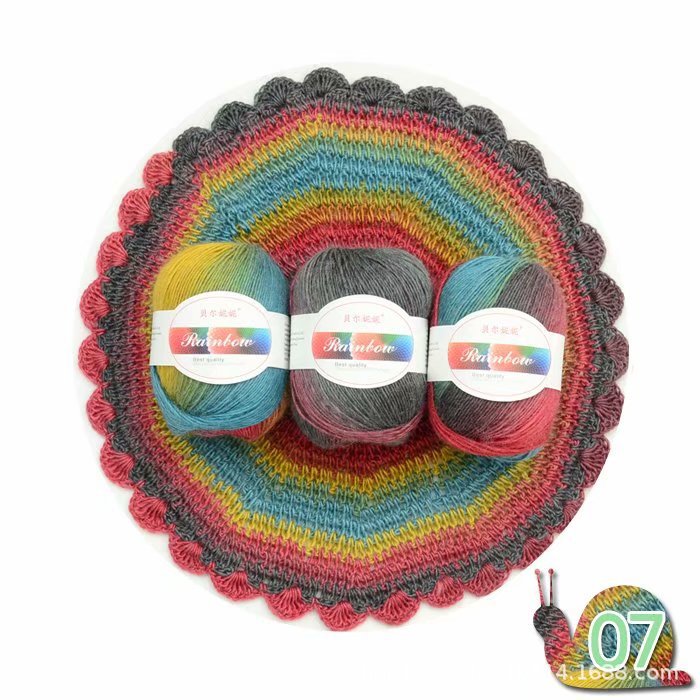 Three skeins of yarn in rainbow colors on a matching crochet dish with a snail logo in the corner.