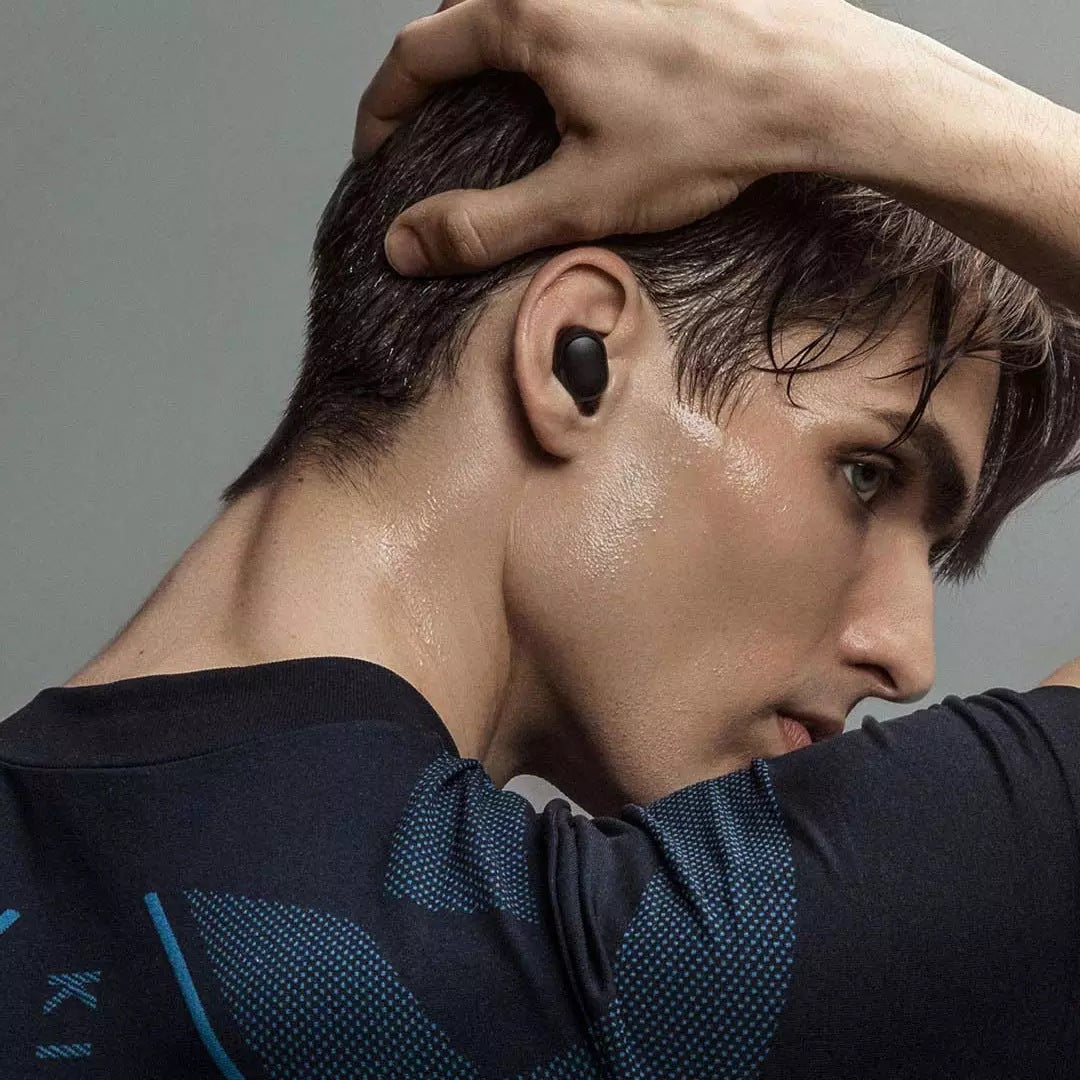 Person wearing a black earbud with sweat on their face and shirt